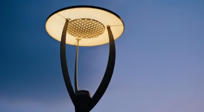 Close-up of a contemporary street lamp illuminating against a clear evening sky.