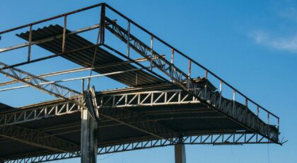 A low angle shot of a modern building's steel framework under a clear blue sky.