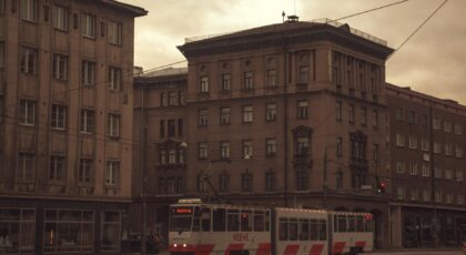 Vintage tram travels past historic architecture in an urban street setting in Estonia.