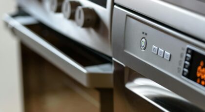 Close-up view of modern stainless steel kitchen appliances with focus on dishwasher and oven.