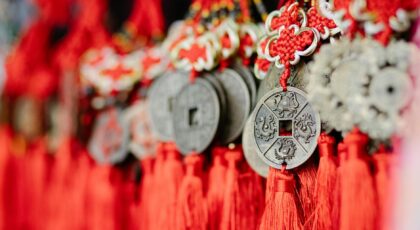 Collection of assorted round amulets in shape of Chinese coins with red satin threads
