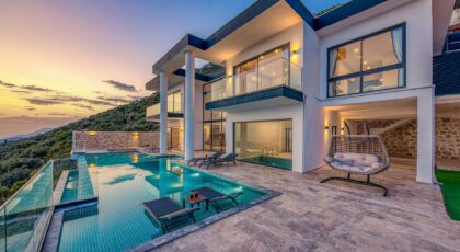 Elegant modern villa featuring an infinity pool and scenic hill views during sunset.