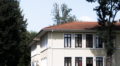 Two-story house in Sakarya with a red roof, surrounded by trees and green lawn.