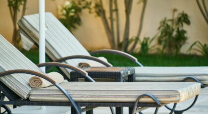 Elegant wooden sun loungers lined up poolside at a tropical resort, perfect for relaxation.