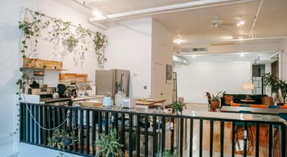 Upstairs interior of comfortable home in Scandinavian style with kitchen and lounge zone decorated with potted plants and lamps hanging around