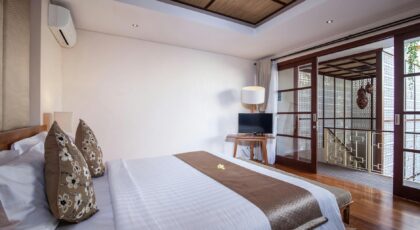 Elegant villa bedroom in Bali with wooden flooring and white linen.