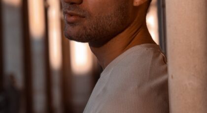 Portrait of a contemplative man leaning against a pillar, bathed in sunset light.