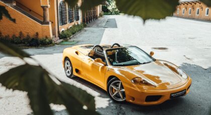 Bright yellow convertible sports car parked in an outdoor courtyard. Elegant architectural background.