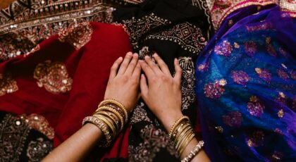 Top view of hands adorned with bangles resting on vibrant traditional fabrics, showcasing cultural fashion.