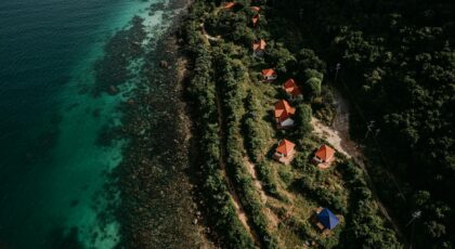 Stunning aerial view of Vietnam's lush coastline with red-roofed houses and clear turquoise waters.