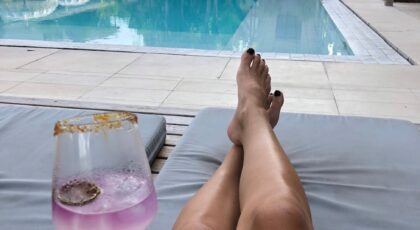 Enjoy a serene moment by a luxurious pool at a Bali resort, cocktail in hand.