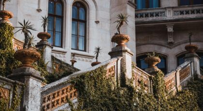 Historic villa exterior with ivy-clad stone staircase and potted plants.