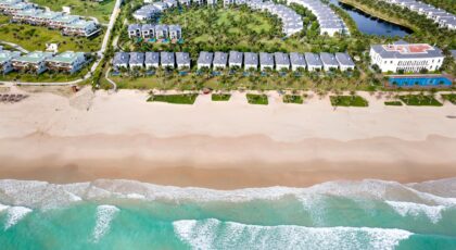 Drone shot capturing a serene beach and luxury resort layout, ideal for summer getaways.