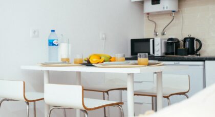 A modern kitchen with a neatly arranged table setting featuring fruit and juice, capturing a minimalist interior design.