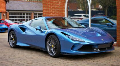 A modern blue sports car parked outdoors in an urban environment.