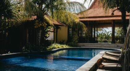 Relax by a luxurious tropical pool surrounded by lush palm trees under a sunny sky, perfect for summer getaways.