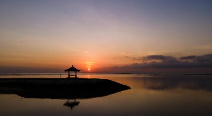 Peaceful sunrise over an ocean view with a gazebo silhouette, perfect scenic beauty.
