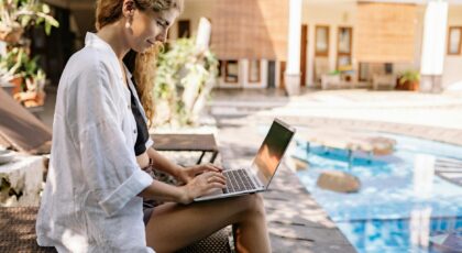 Woman with curly hair working on a laptop by the pool in Bali, Indonesia.