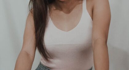 Fashionable woman wearing sunglasses poses with a confident attitude indoors.