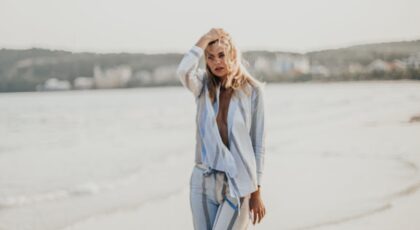 Fashionable woman poses on a sandy beach in Bali, Indonesia, showcasing style and elegance.
