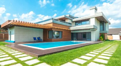 Contemporary house with pool, lush lawn, and clear skies.
