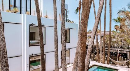 Elegant modern house with pool and palm trees under a bright blue sky.