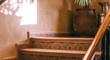 Cozy indoor staircase with tiled steps and potted palm, bathed in warm sunlight.