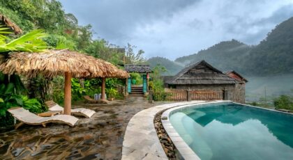 Serene tropical resort with poolside view amidst lush greenery and mountain backdrop.