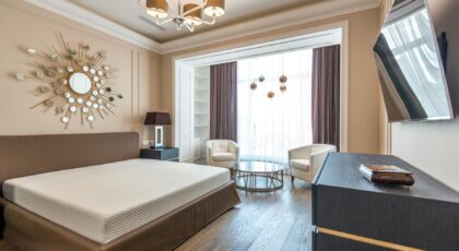 Contemporary hotel room with stylish furnishings and decor featuring a chic chandelier and large window.