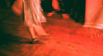 Blurred image capturing the dynamic motion of dancing in vibrant red lighting.