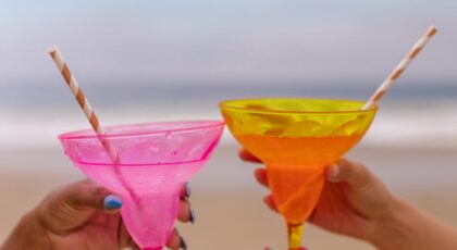 Vibrant cocktails with orchids held on a beach, symbolizing relaxation and luxury.
