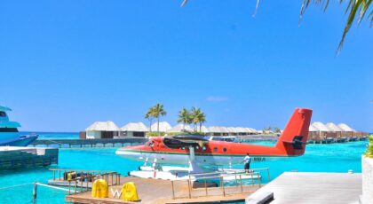 Seaplane docked at a vibrant tropical island resort under a clear blue sky, perfect for vacations.