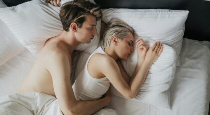 Couple embracing while sleeping peacefully in a cozy bedroom setting.