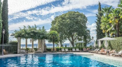 Enjoy a serene day by the luxurious tropical resort poolside, surrounded by palm trees and clear blue skies.