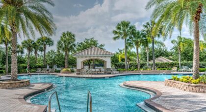 Relaxing tropical poolside scene with palm trees, gazebo, and clear blue water at a luxury resort.