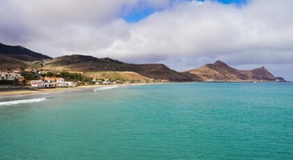 Breathtaking view of Porto Santo's coastline with turquoise waters and mountainous backdrop, Madeira, Portugal.