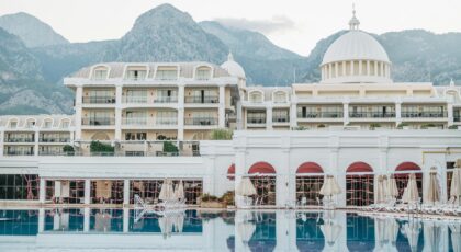 Elegant resort facade with pool, surrounded by mountains, perfect for a luxurious vacation getaway.