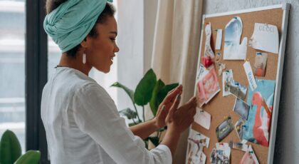 A woman arranging a creative mood board with diverse images and notes in a stylish interior.