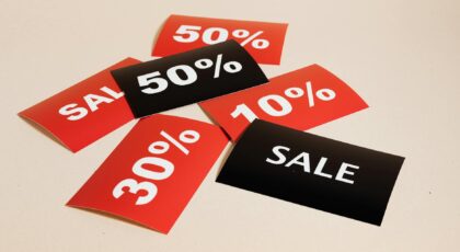 Red and black sale tags showing various discount percentages on a beige background.