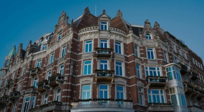 Charming historic hotel facade in Amsterdam with festive decorations, bright windows, and classic architecture.