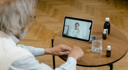 An elderly man participates in a telemedicine session using a tablet.
