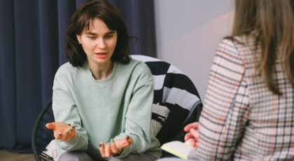 Calm female sitting on armchair and giving interview to concentrated woman in light room