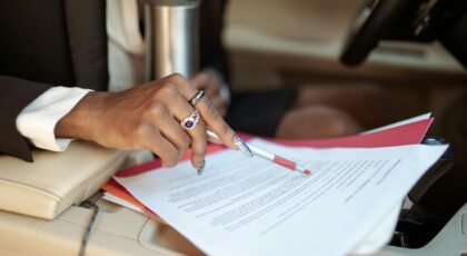 A professional reviewing documents in a car interior, focusing on hand and paperwork.
