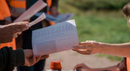 Group of volunteers handing out missing person flyers during a search operation outdoors.