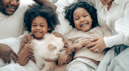 Happy family bonding time with kids and a Pomeranian dog in cozy home setting.