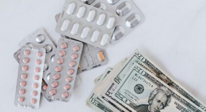 Top view of different blisters of medications and pills composed with heap of paper money