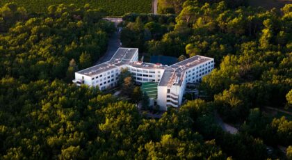 Aerial shot of a modern hotel nestled in a lush green forest.