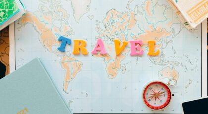 Flat lay of a map with colorful letters "TRAVEL" and a compass for planning adventures.