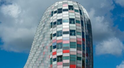 Vibrant modern skyscraper with colorful glass facade in Utrecht, Netherlands under a bright sky.
