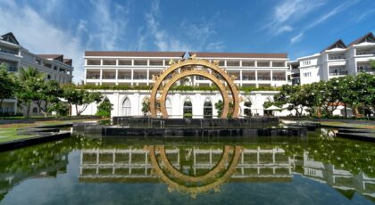Elegant hotel facade with a stunning fountain reflecting in a serene pool, perfect for relaxation and vacation.